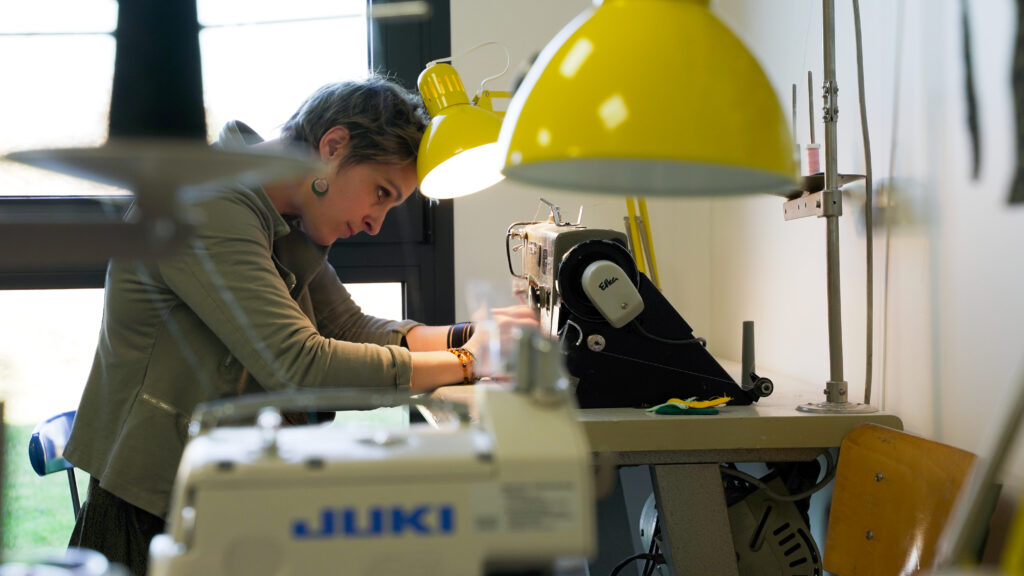 Julie tavet la creatrice de la marque BIDZOUKI au travail à l'atelier derrière sa machine à coudre